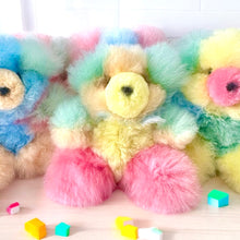 Load image into Gallery viewer, Colorful alpaca plush bears line up on a light wooden surface, surrounded by pastel blocks.